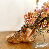 Antique bronzed baby shoe dried flower and foliage arrangement